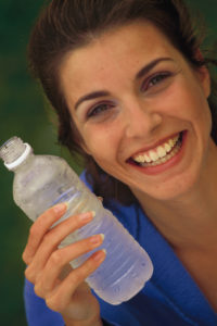 Closeup of a brunette woman smiling holding a cold plastic water bottle